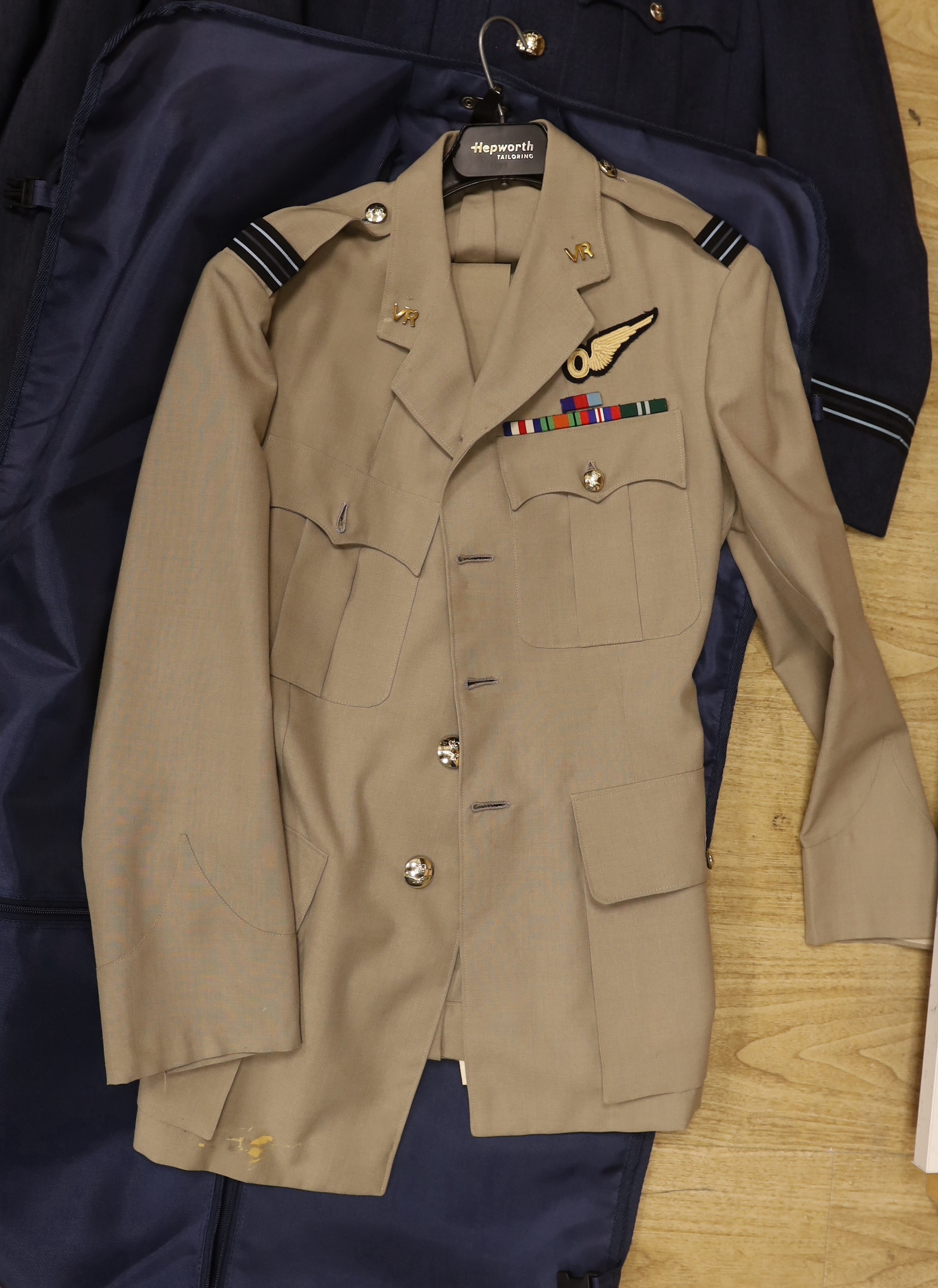 A collection of post-war RAF uniforms, comprising; two caps, double-breasted overcoat, dress uniform of jacket, trousers and gloves, two sets of jacket and trousers with ribbons for WWII awards, plus a pair of navigator’